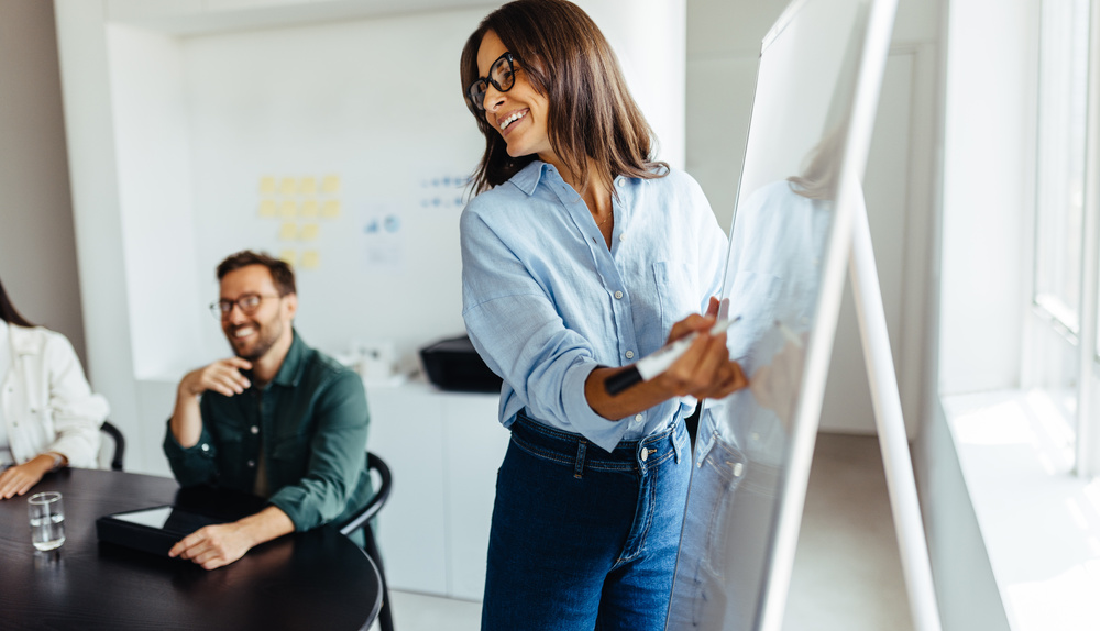 Frau schreibt auf eine weiße Tafel